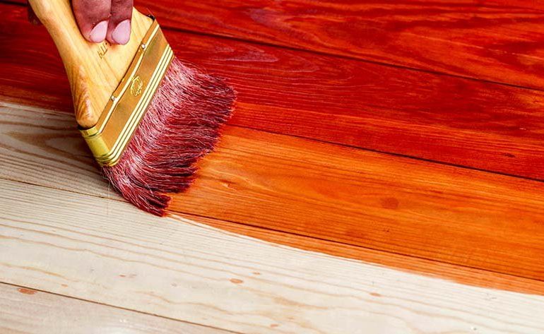 The best oil for wooden floors and an wood floor oil being applied with a brush